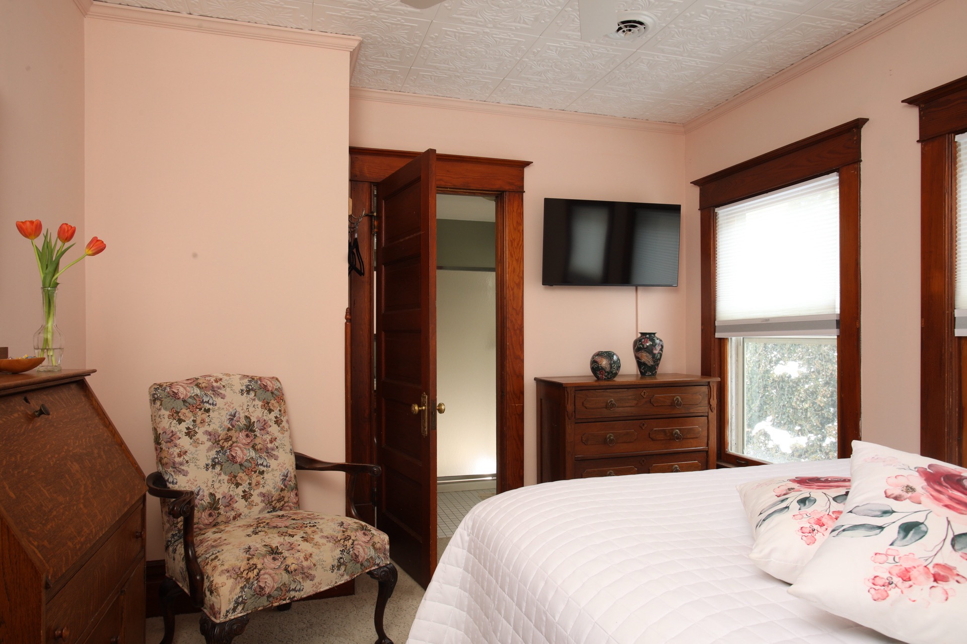 Bedroom with a faux tin ceiling, Queen bed, sitting chair and private bath.