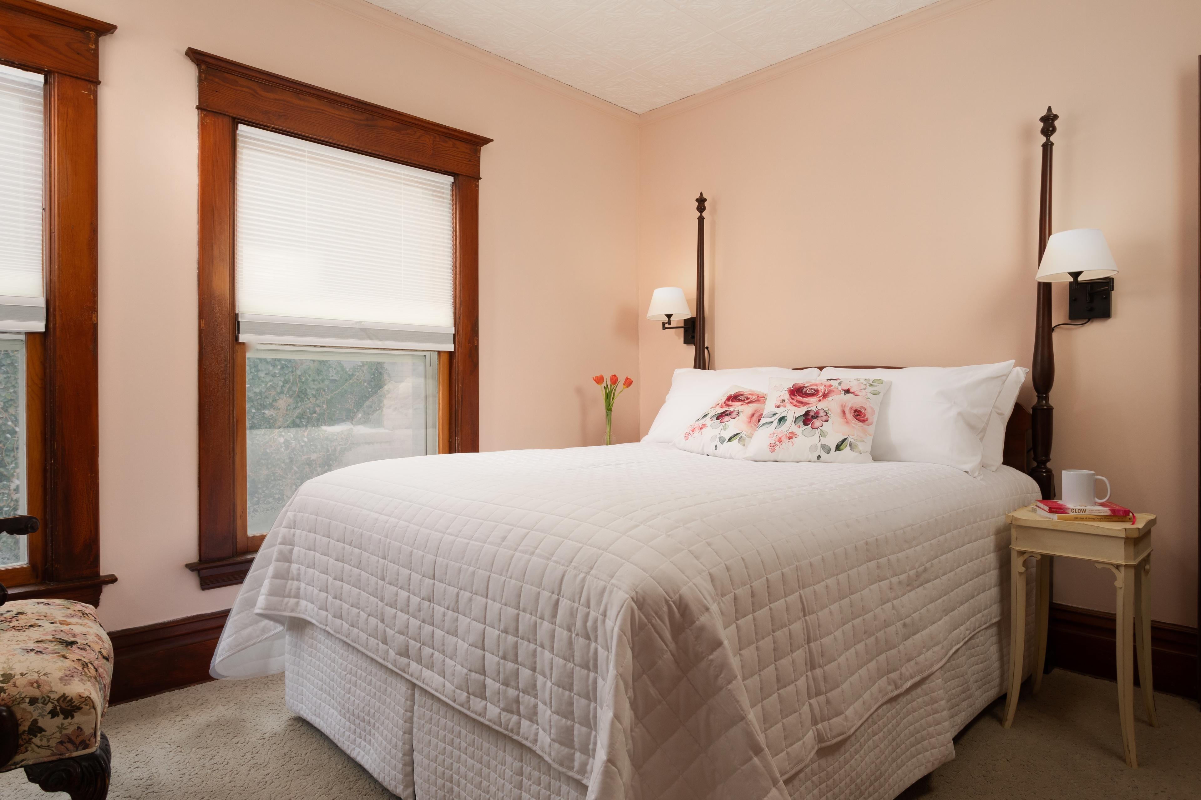 Bedroom with a faux tin ceiling, Queen bed, sitting chair and private bath.