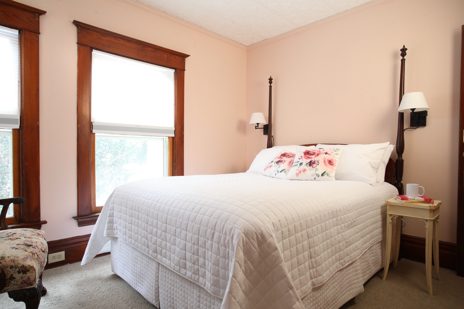 Bedroom with a faux tin ceiling, Queen bed, sitting chair and private bath.