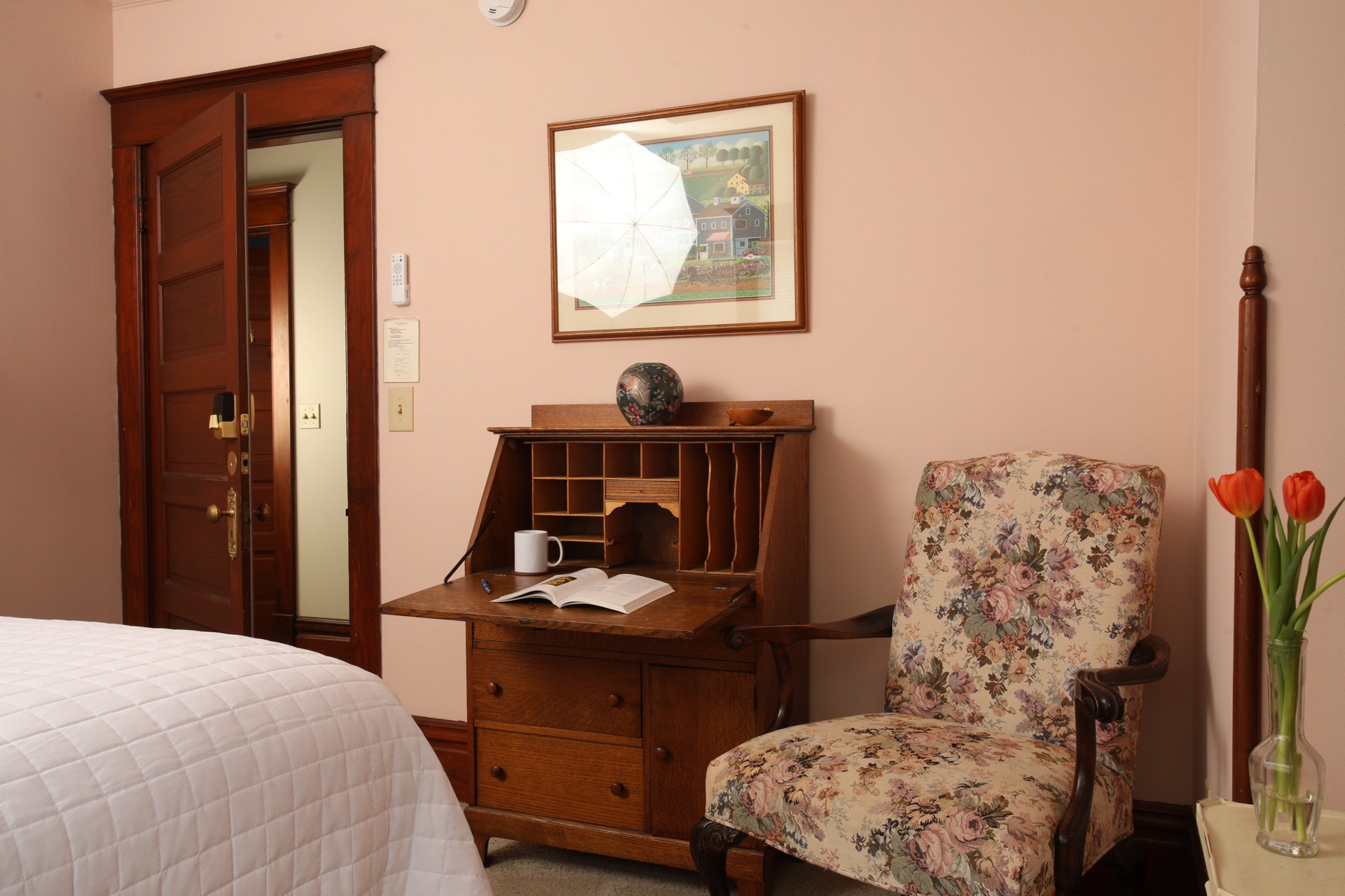 Bedroom with a faux tin ceiling, Queen bed, sitting chair and private bath.