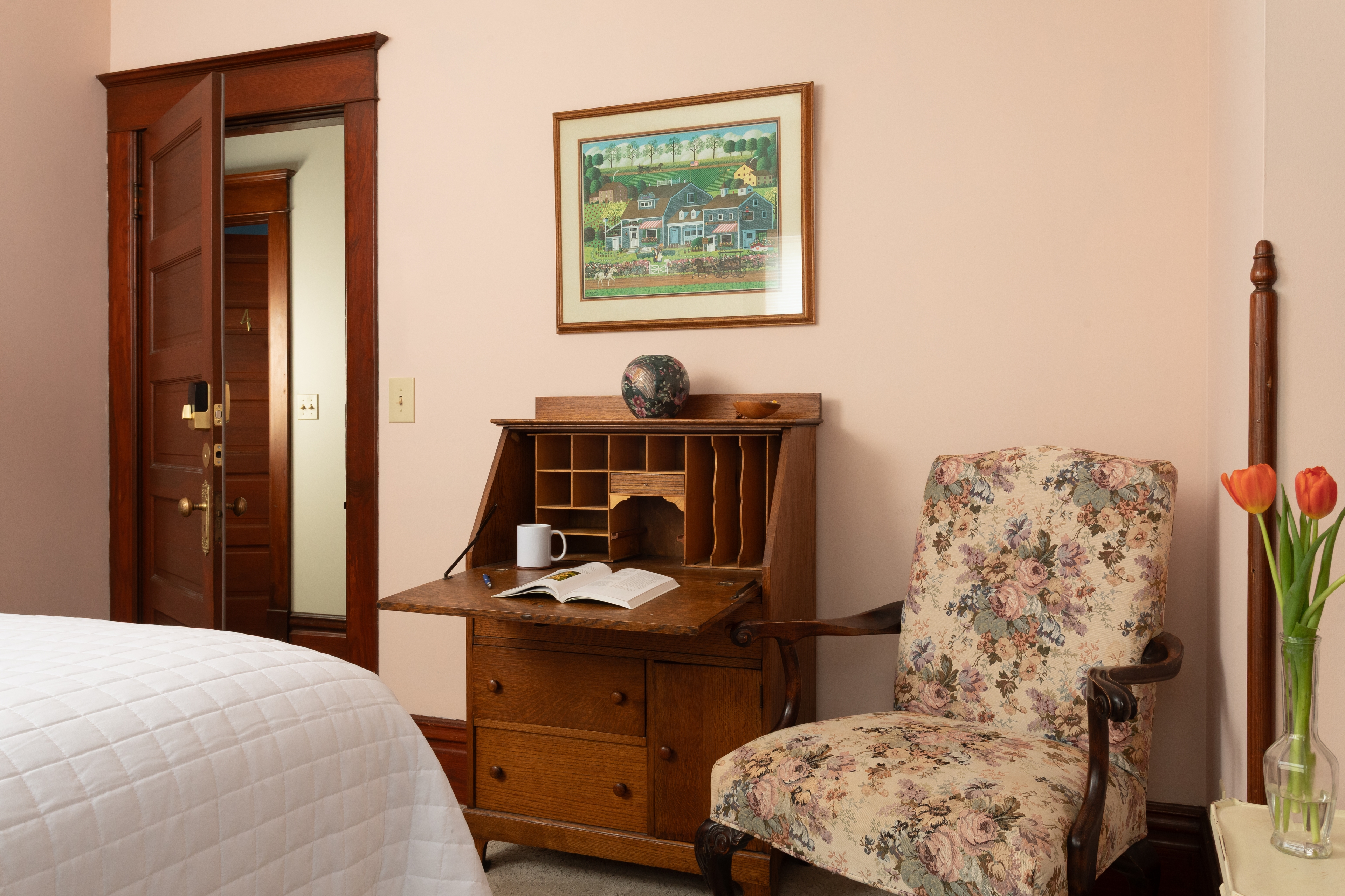 Bedroom with a faux tin ceiling, Queen bed, sitting chair and private bath.