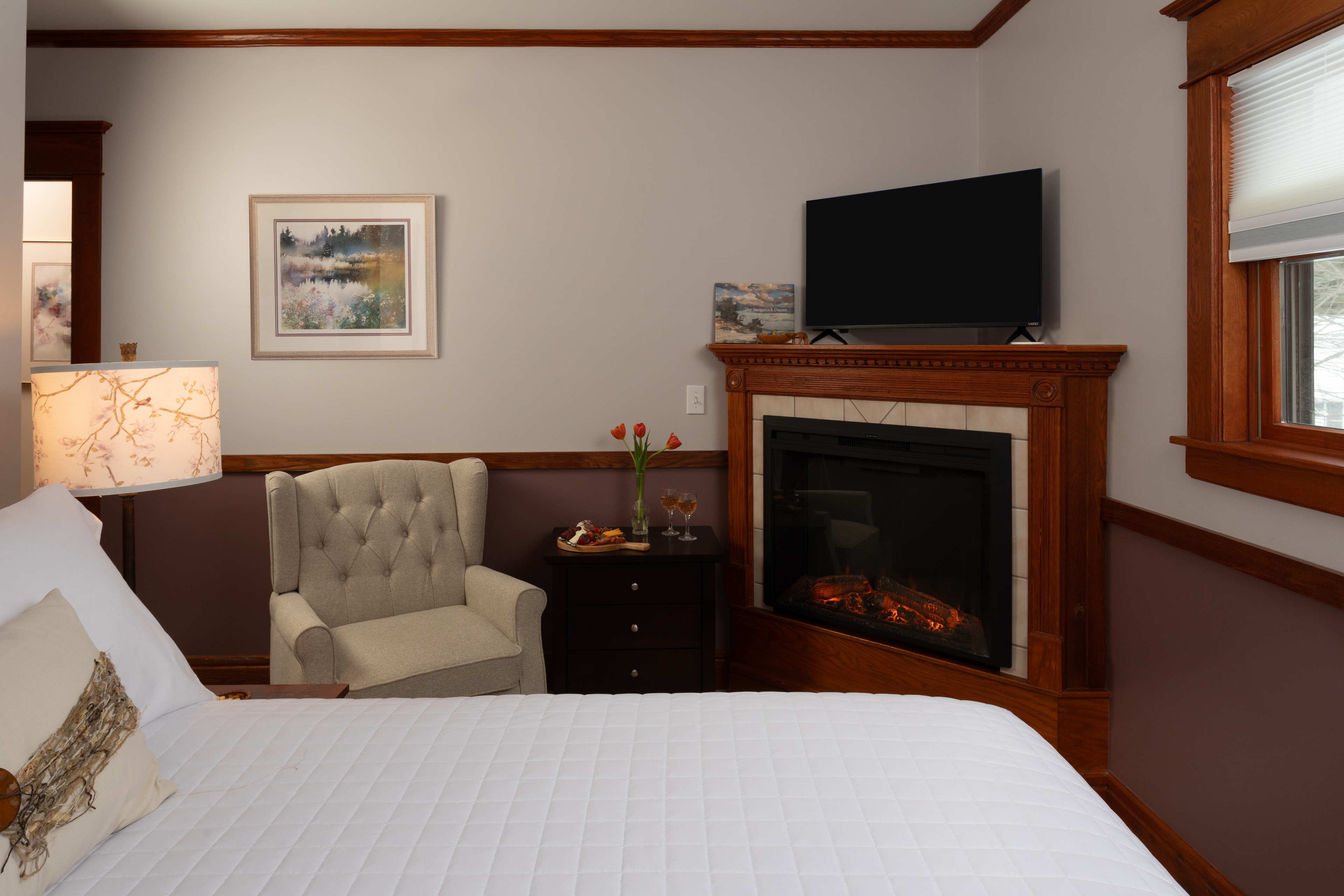 Two tone bedroom with a 2 post Heckman bed,  a fireplace, and a flat-screen TV.