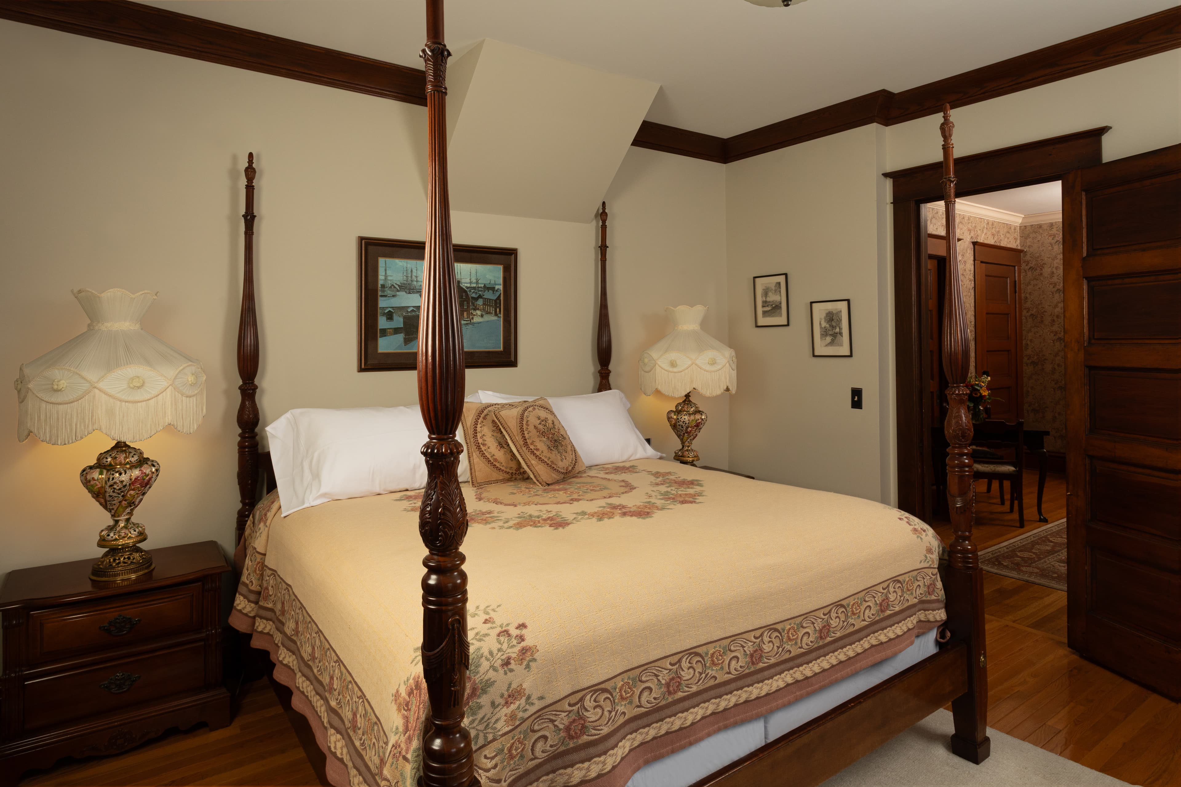 Four-poster bed with ornate lamps on bedside tables and a patterned rug.