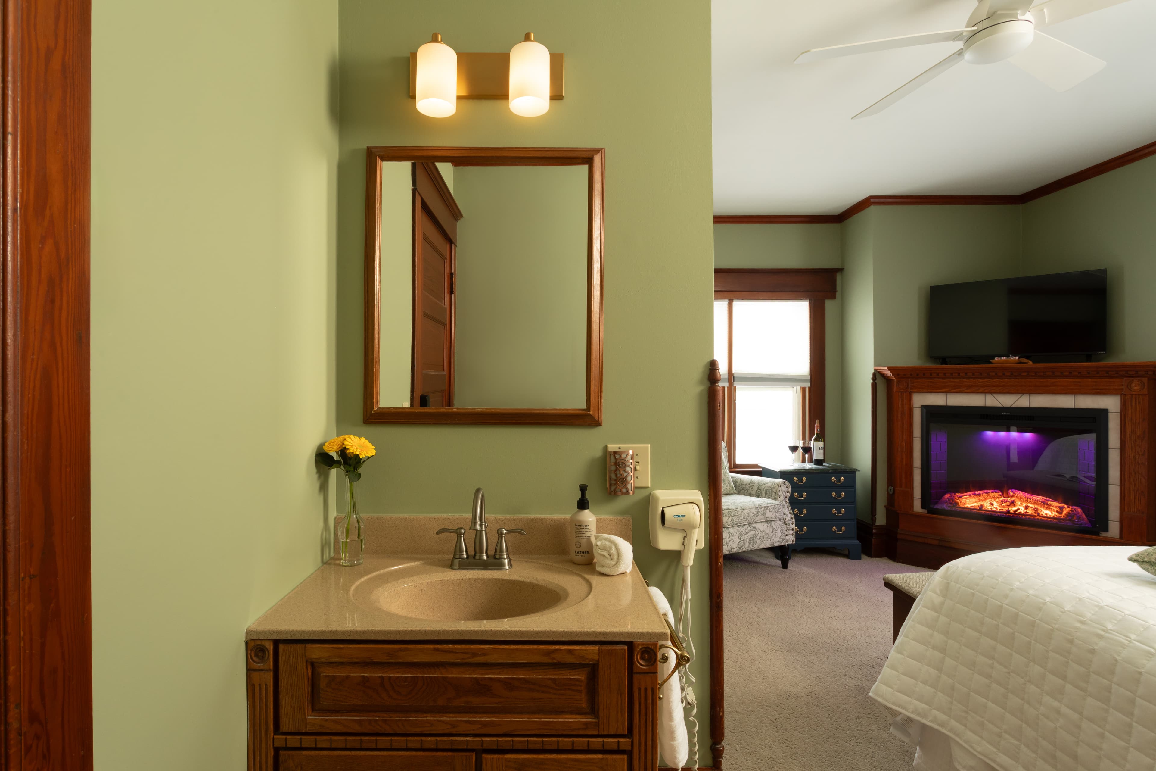 Bedroom with Clary Sage walls, a fireplace, and a sink vanity facing Butler Street.