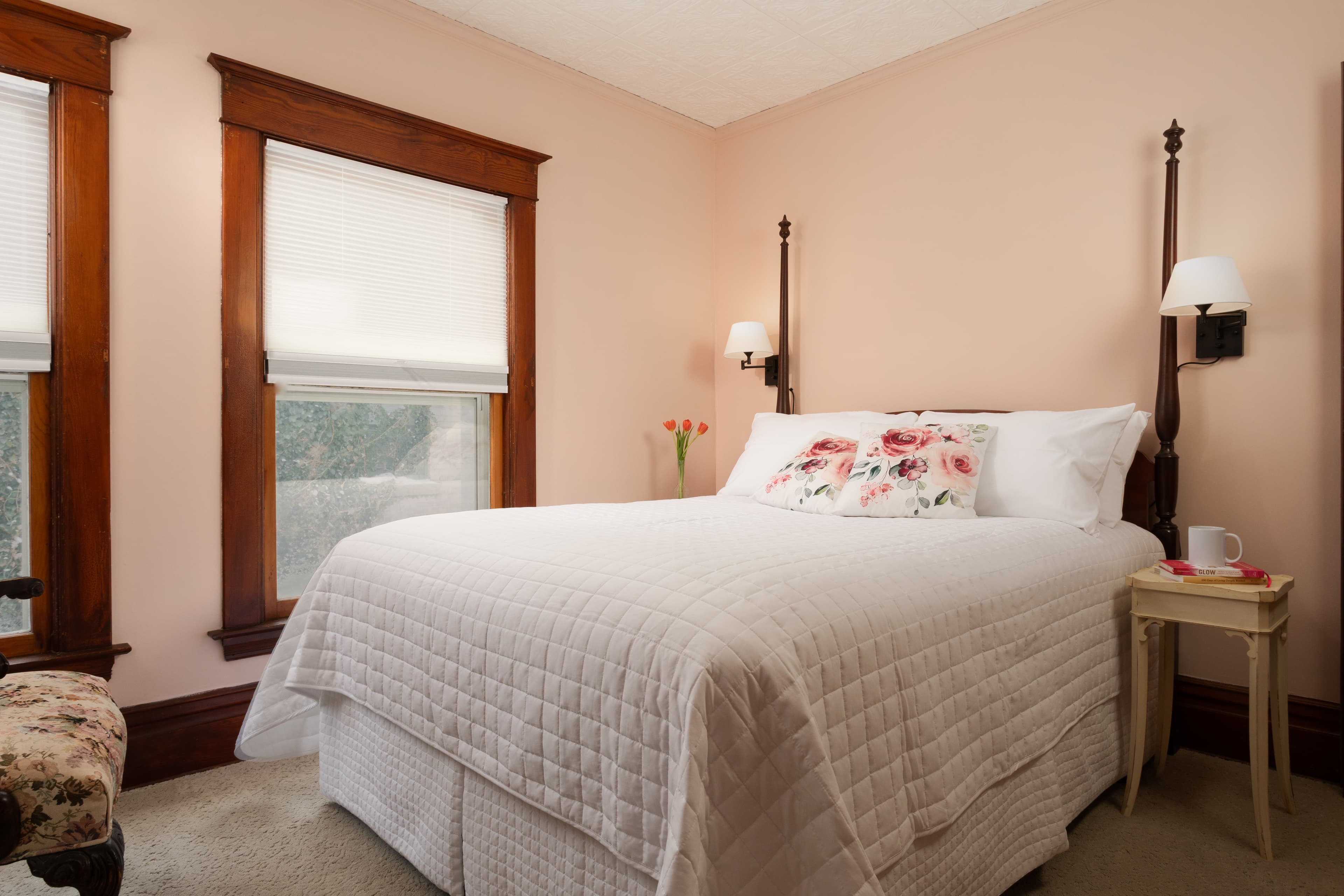 Bedroom with a faux tin ceiling, Queen bed, sitting chair and private bath.
