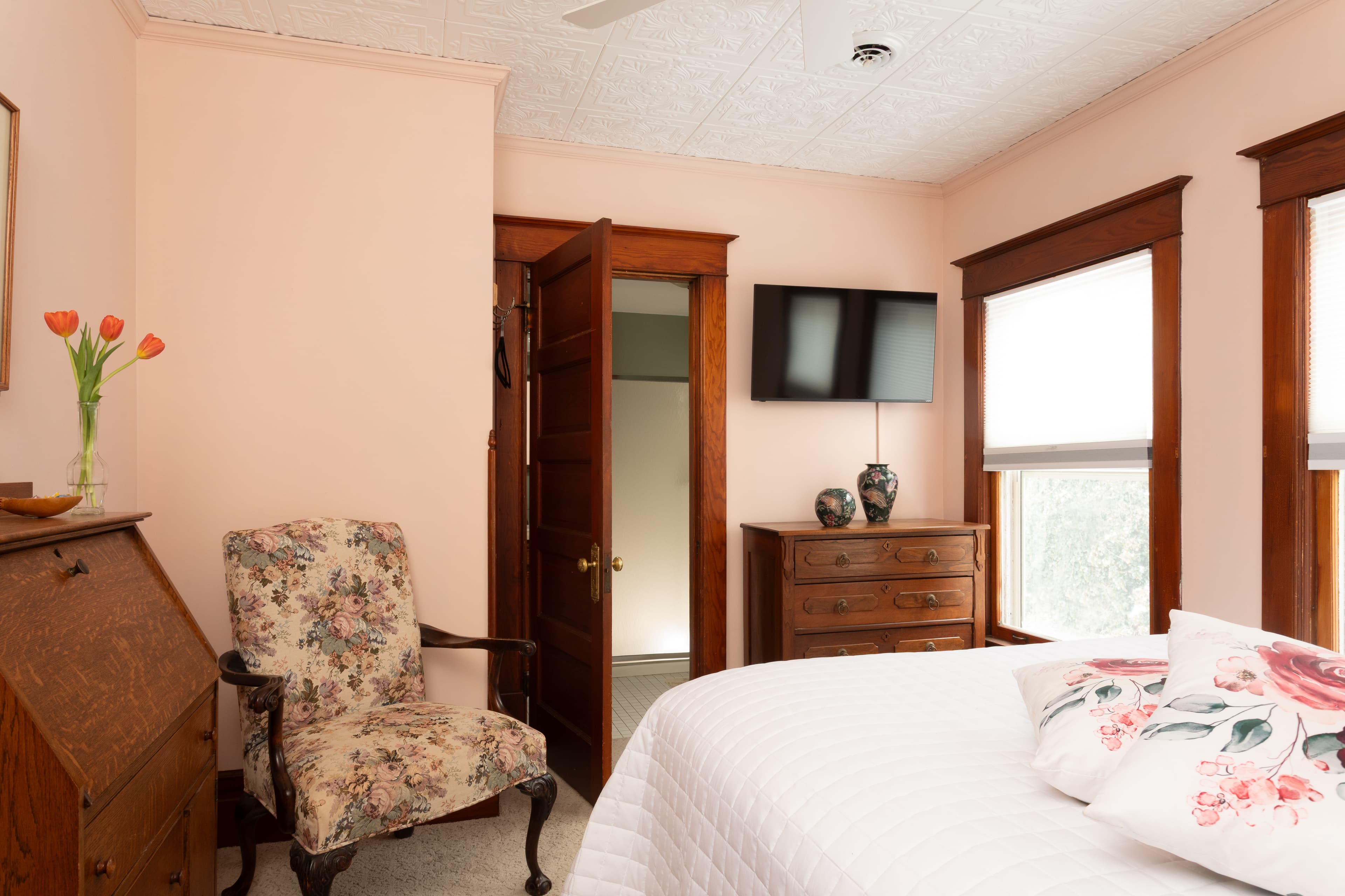 Bedroom with a faux tin ceiling, Queen bed, sitting chair and private bath.