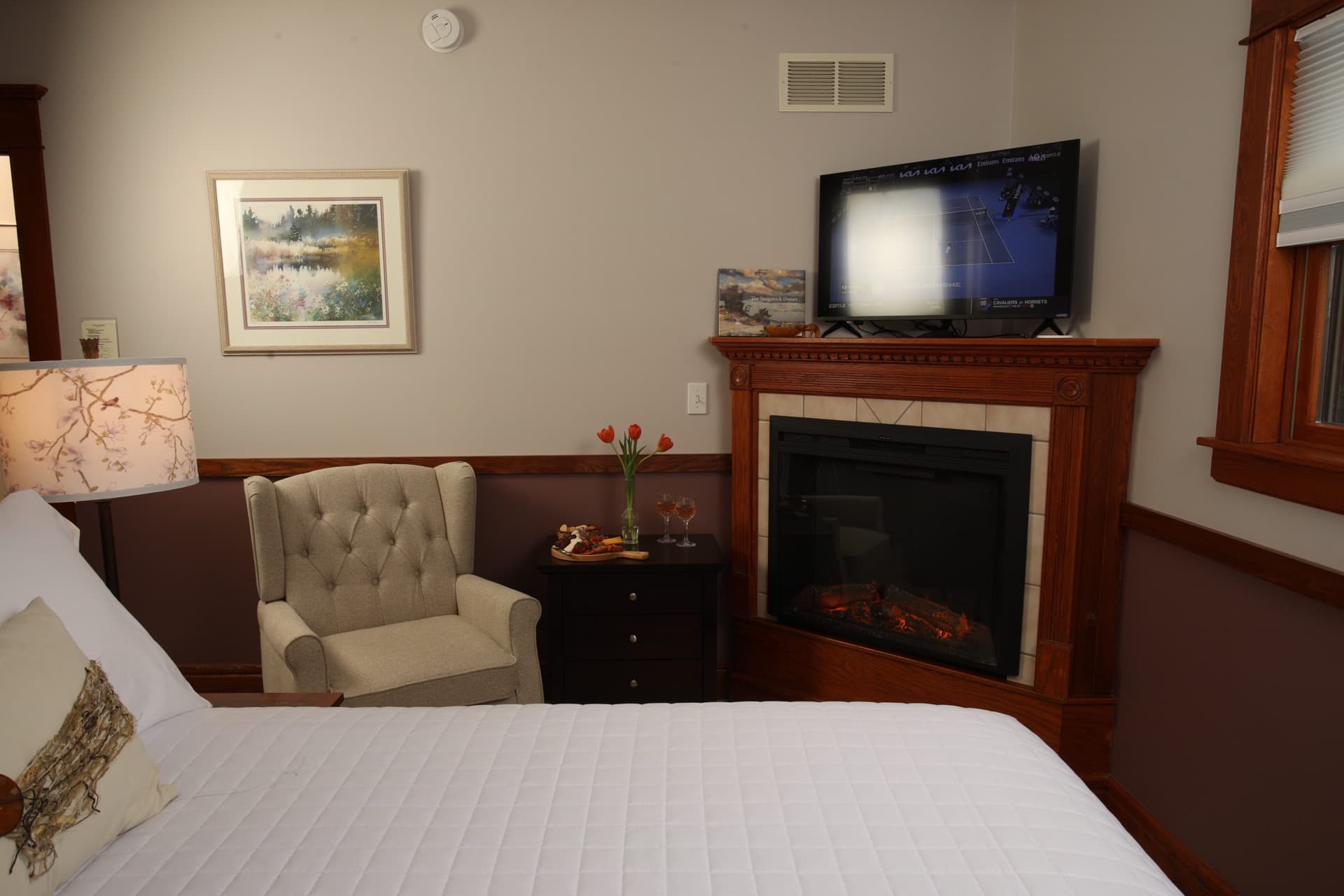 Two tone bedroom with a 2 post Heckman bed,  a fireplace, and a flat-screen TV.
