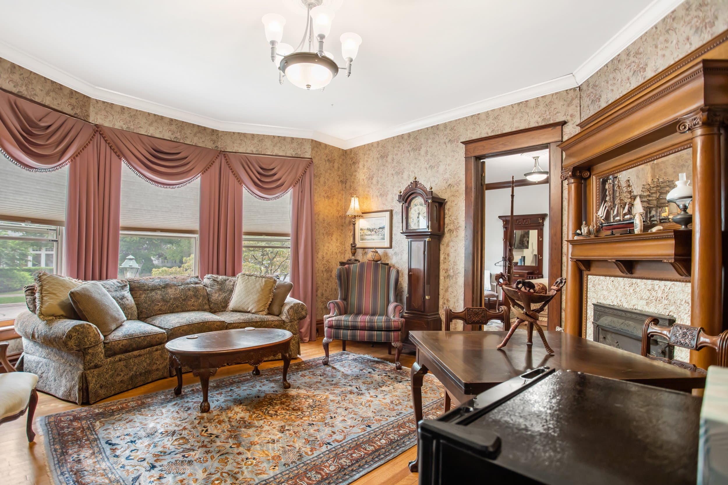 Ornate living room with patterned wallpaper, large rug, and antique furniture.