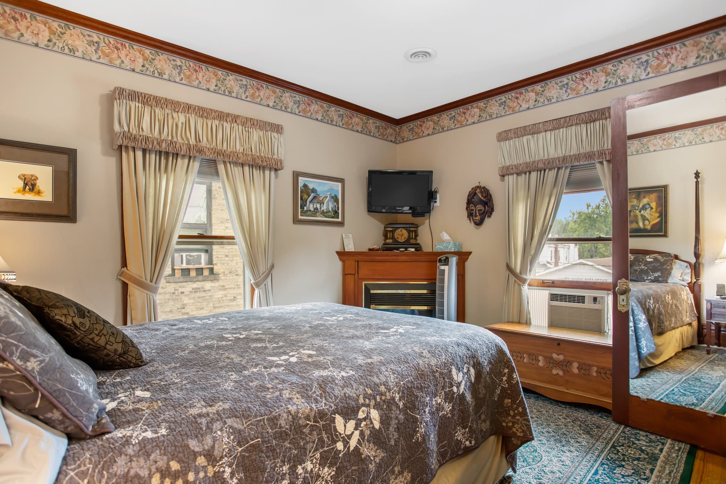 Bedroom with a large bed, fireplace, and a mirror reflecting another bed.