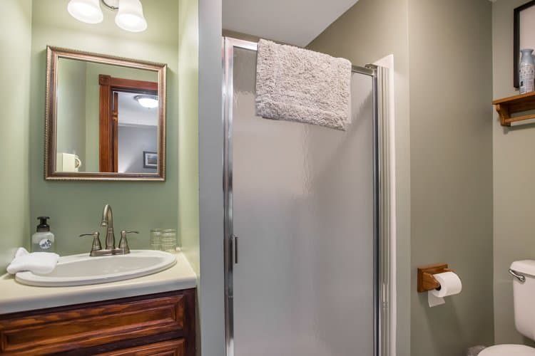 Bathroom with light green walls, a sink vanity, and a shower with a frosted glass door.