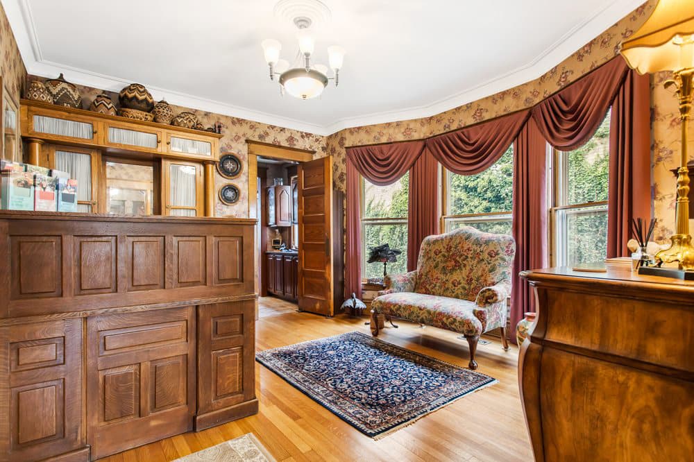 A warmly decorated room featuring wooden furnishings, floral curtains, and a comfortable seating area.