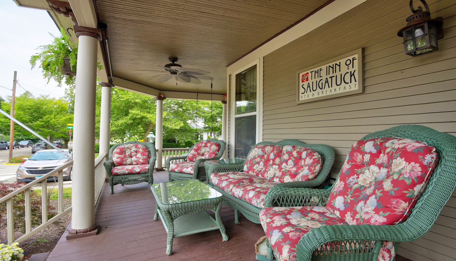 A cozy porch at The Inn of Saugatuck featuring floral-patterned wicker furniture and a welcoming atmosphere.